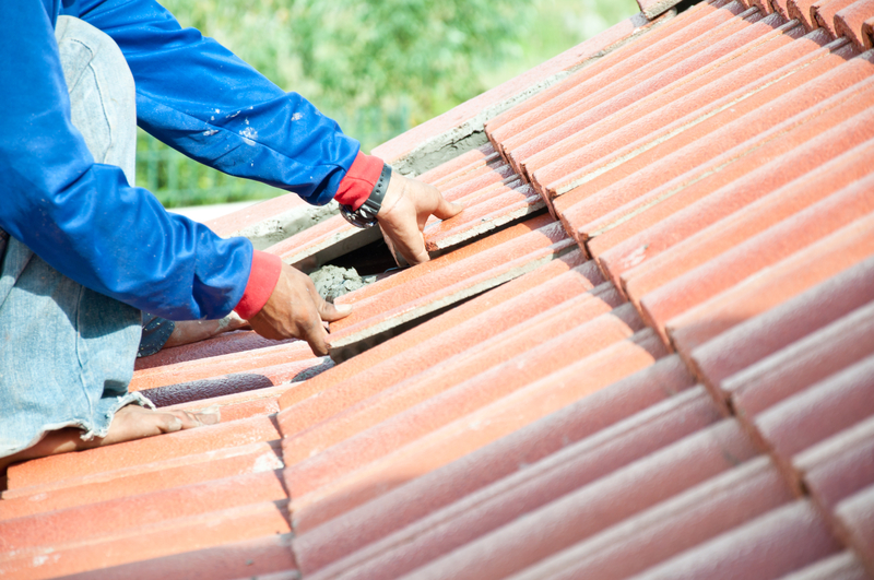 Roof repair. Worker repairing tile on roof
